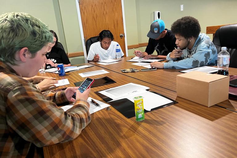 Group of students sitting around table learning.